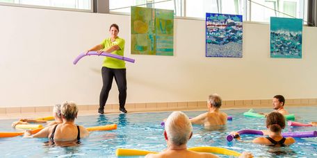 Therapeutin motiviert Patienten bei der Wassergymnastik