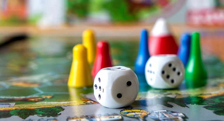 Würfel und Spielfiguren auf einem Spielbrett