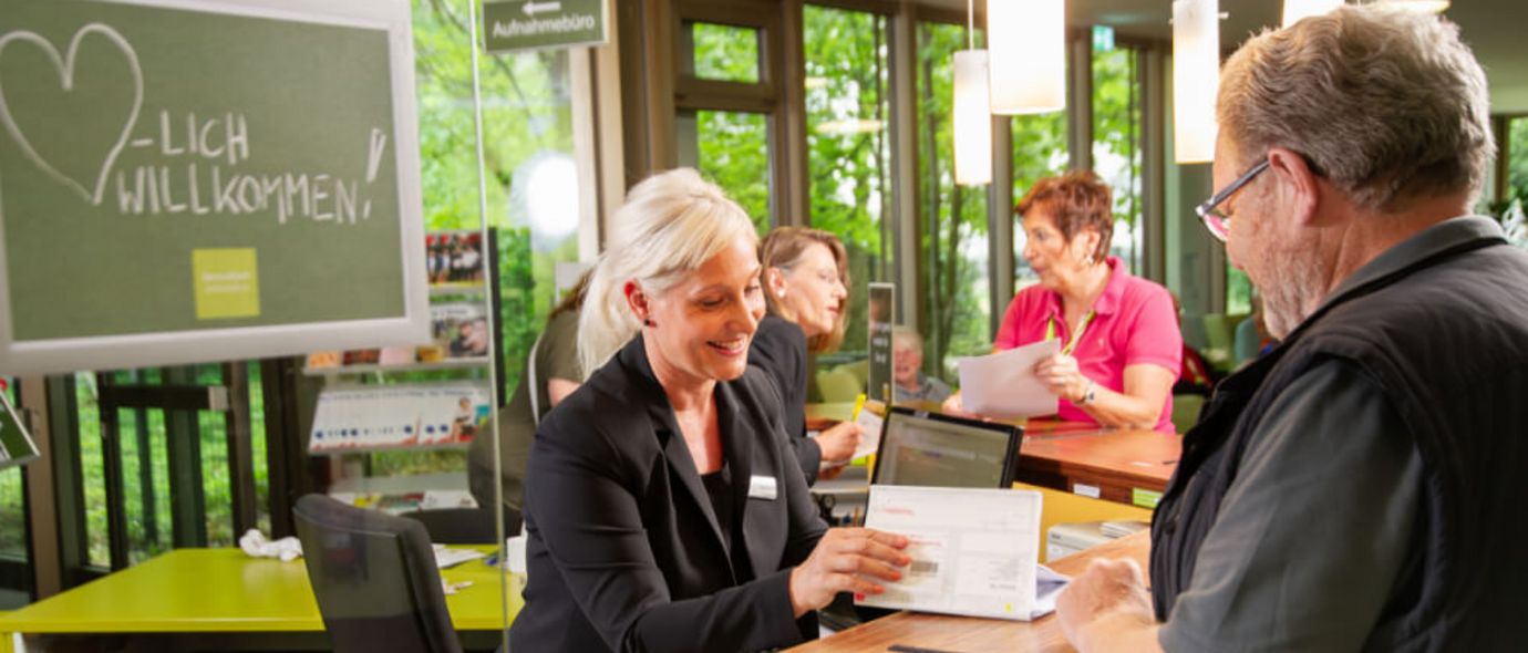 Rezeptionsmitarbeiterin berät Patienten am Empfang